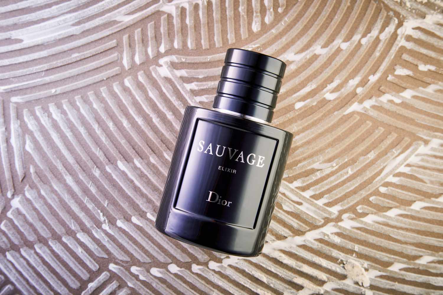 DIOR Sauvage Elixir displayed on a patterned brown surface